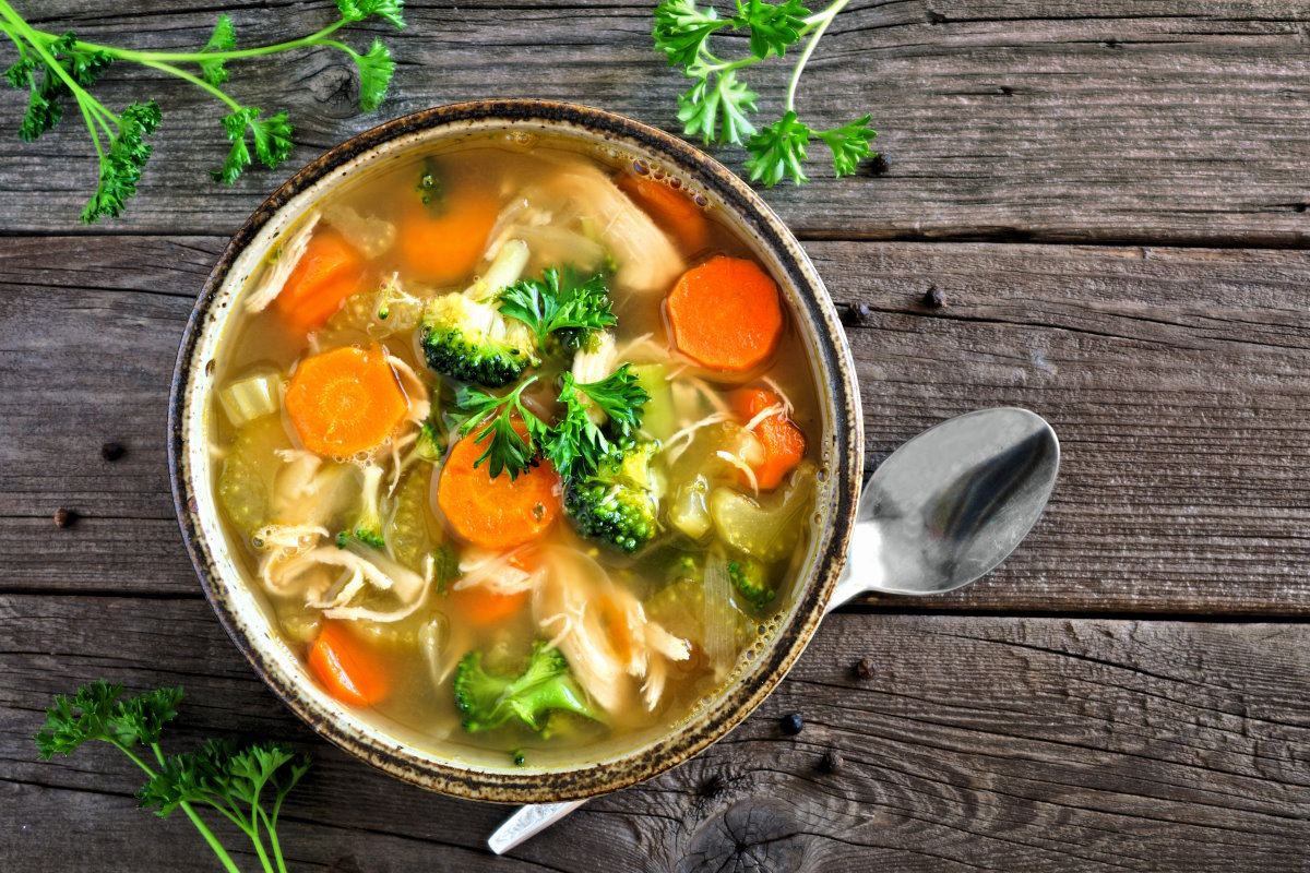 Homemade chicken vegetable soup, top view on rustic wood Homemade chicken vegetable soup, top view on an aged rustic wood background